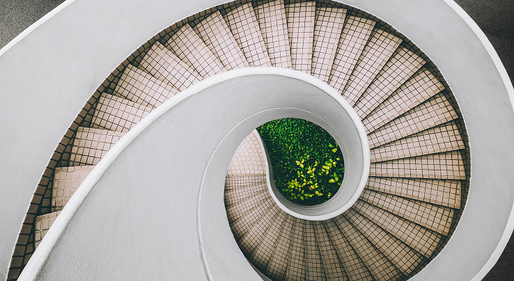 Aerial view of a modern spiral staircase curving around a green courtyard garden.