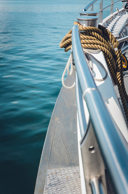 Close-up of a yacht deck with nautical ropes and a calm ocean in the background.